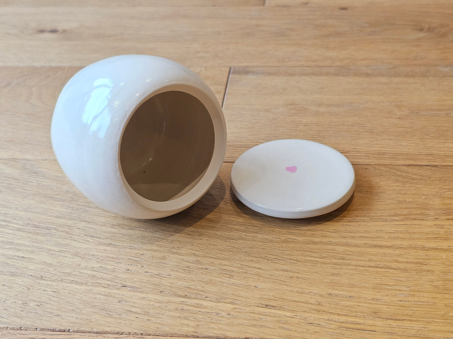 Open ceramic pet urn, with small pink heart on lid