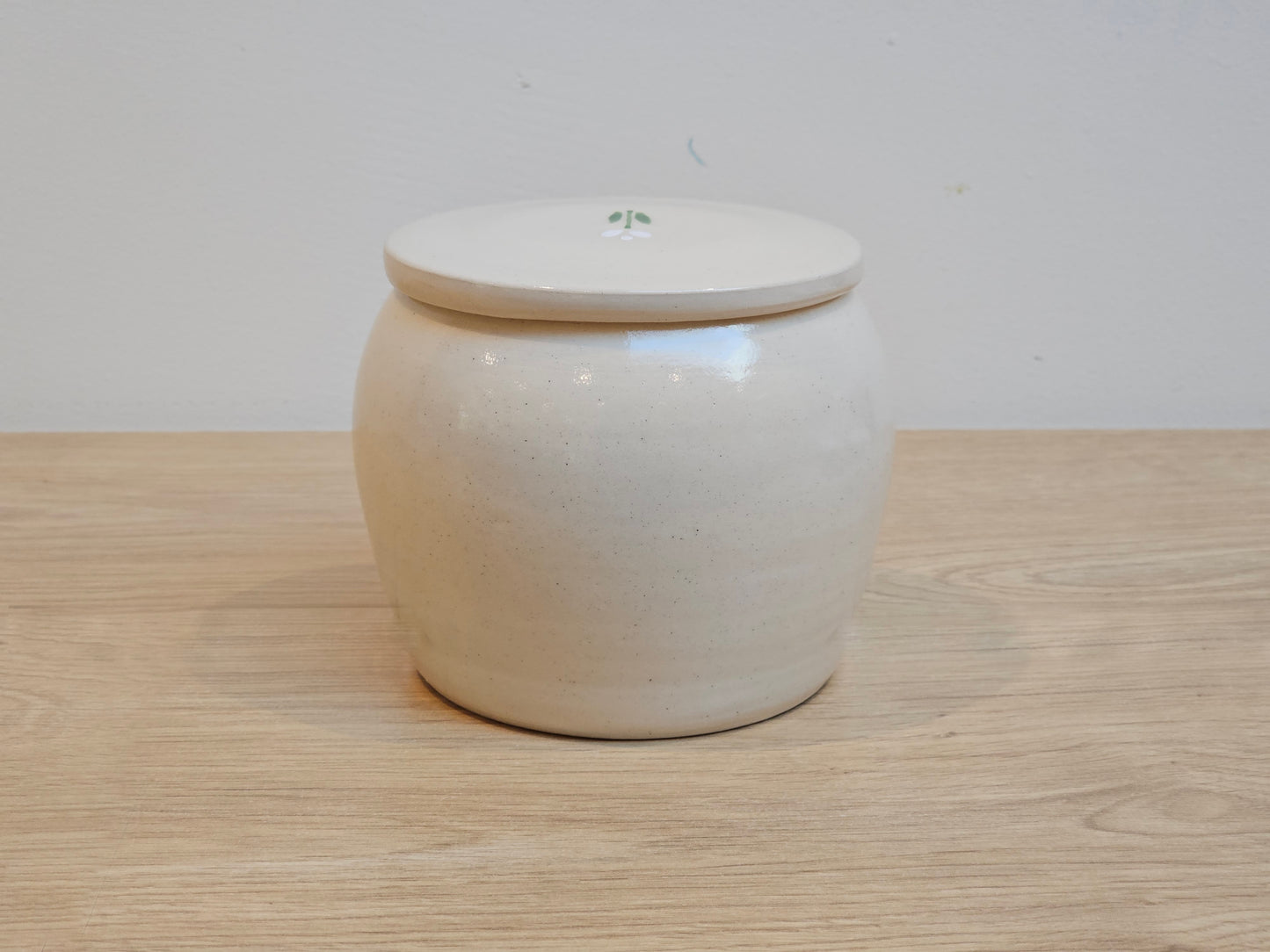 Pottery pet urn with white tulip on lid