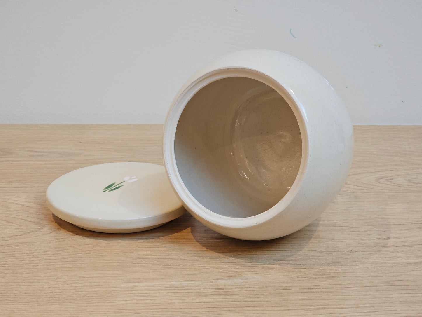 Open ceramic pet urn with white tulip on lid