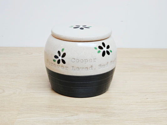 Black and cream hand made pet urn, with black flowers and green detail with inscription: 'Cooper, Forever Loved, Bud Bud'