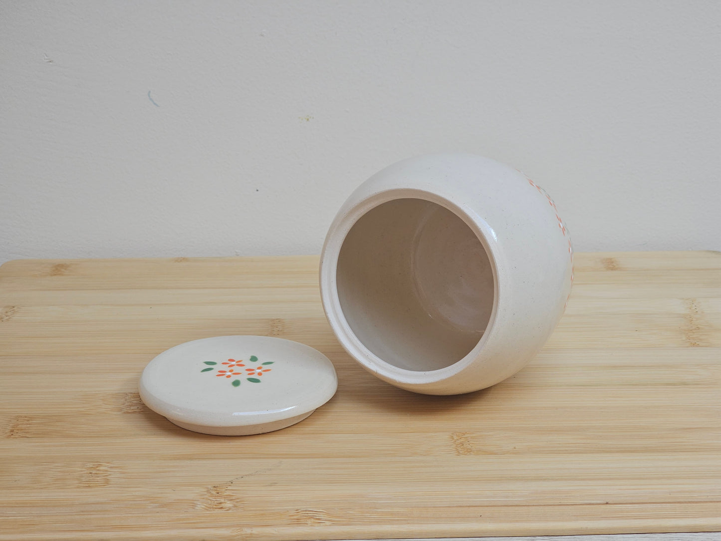 Handmade ceramic pet urn with orange flowers hand-painted around the entire bottom, perfect personalized memorial keepsake for pets.