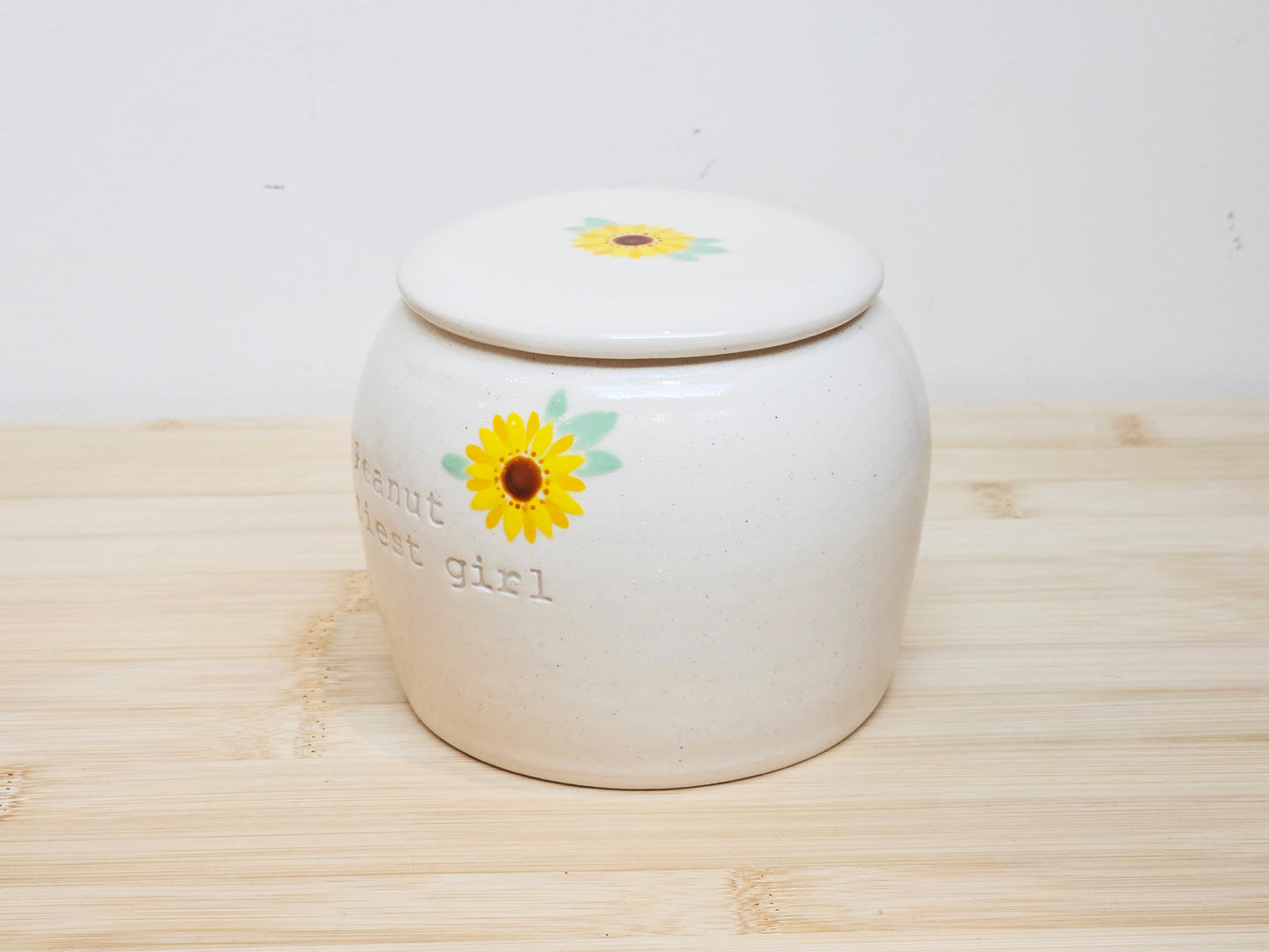 White ceramic cremation for dog and cat ashes with sunflower design and engraved name.