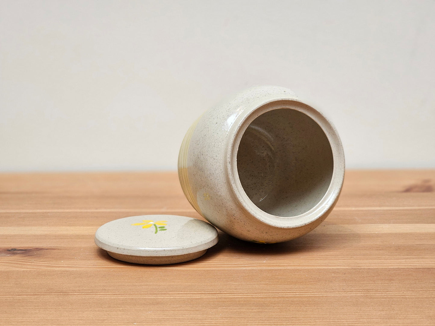 Personalised handmade ceramic pet urn with hand-painted yellow flowers, customisable with name engraving for a unique pet memorial. This decorative pottery pet cremation urn is designed for safely storing dog or cat ashes, featuring a secure lid and a smooth glazed finish. Perfect for pet owners looking for a bespoke, handcrafted pet ashes urn to honour their beloved companion with a timeless and elegant tribute.