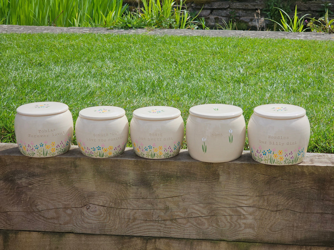 Custom engraved and hand painted pottery pet urns on a wall in a garden