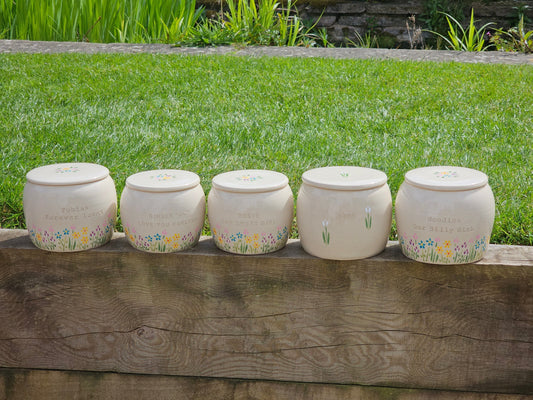 Custom engraved and hand painted pottery pet urns on a wall in a garden