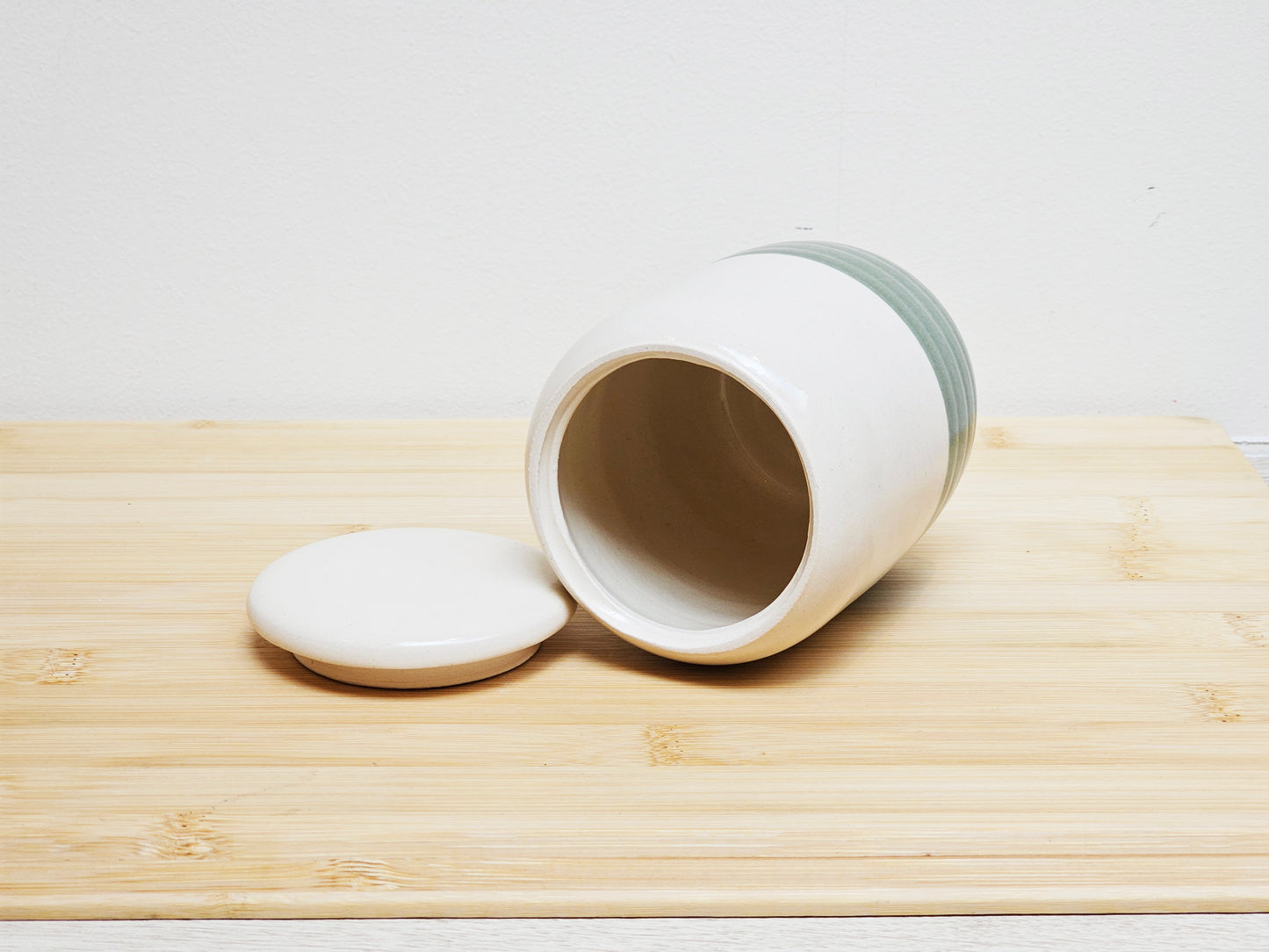 White ceramic container with lid to the side on a wooden surface