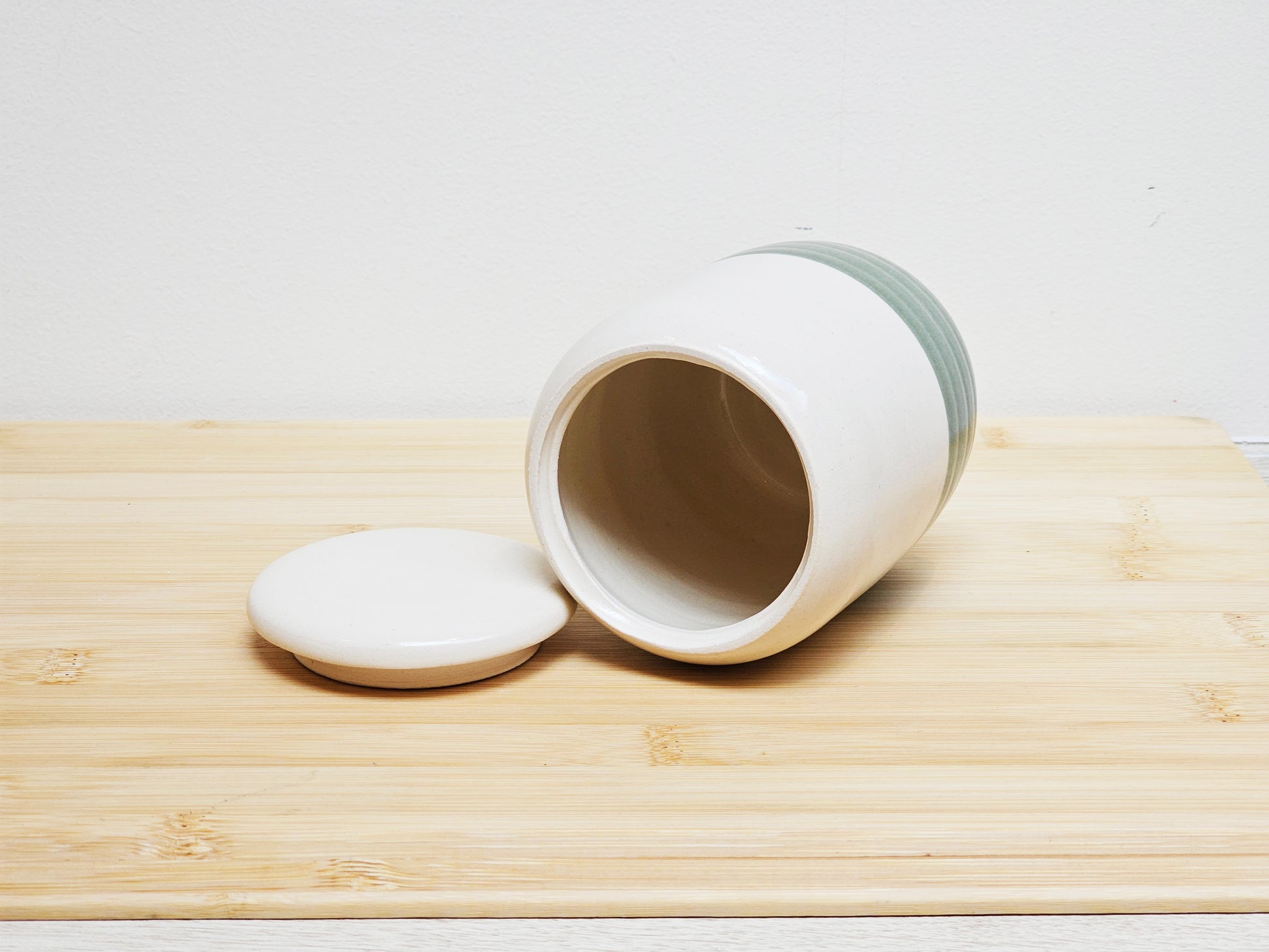 White ceramic container with lid to the side on a wooden surface
