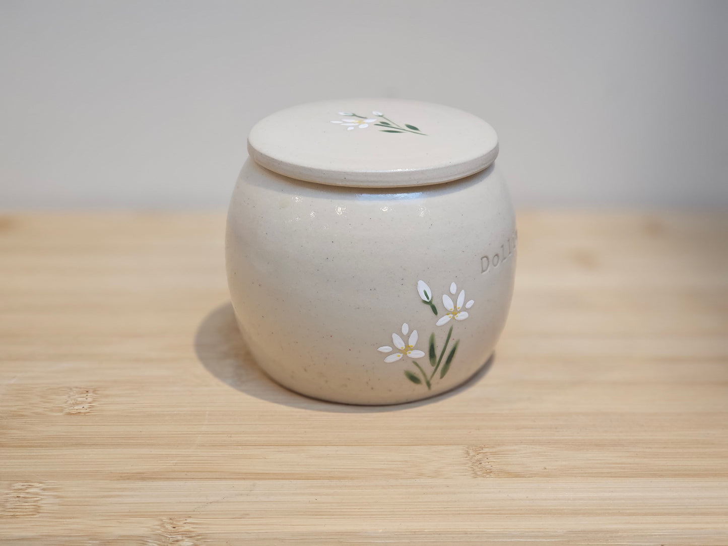 Hand-painted ceramic pet urn decorated with white lilies, personalised memorial keepsake