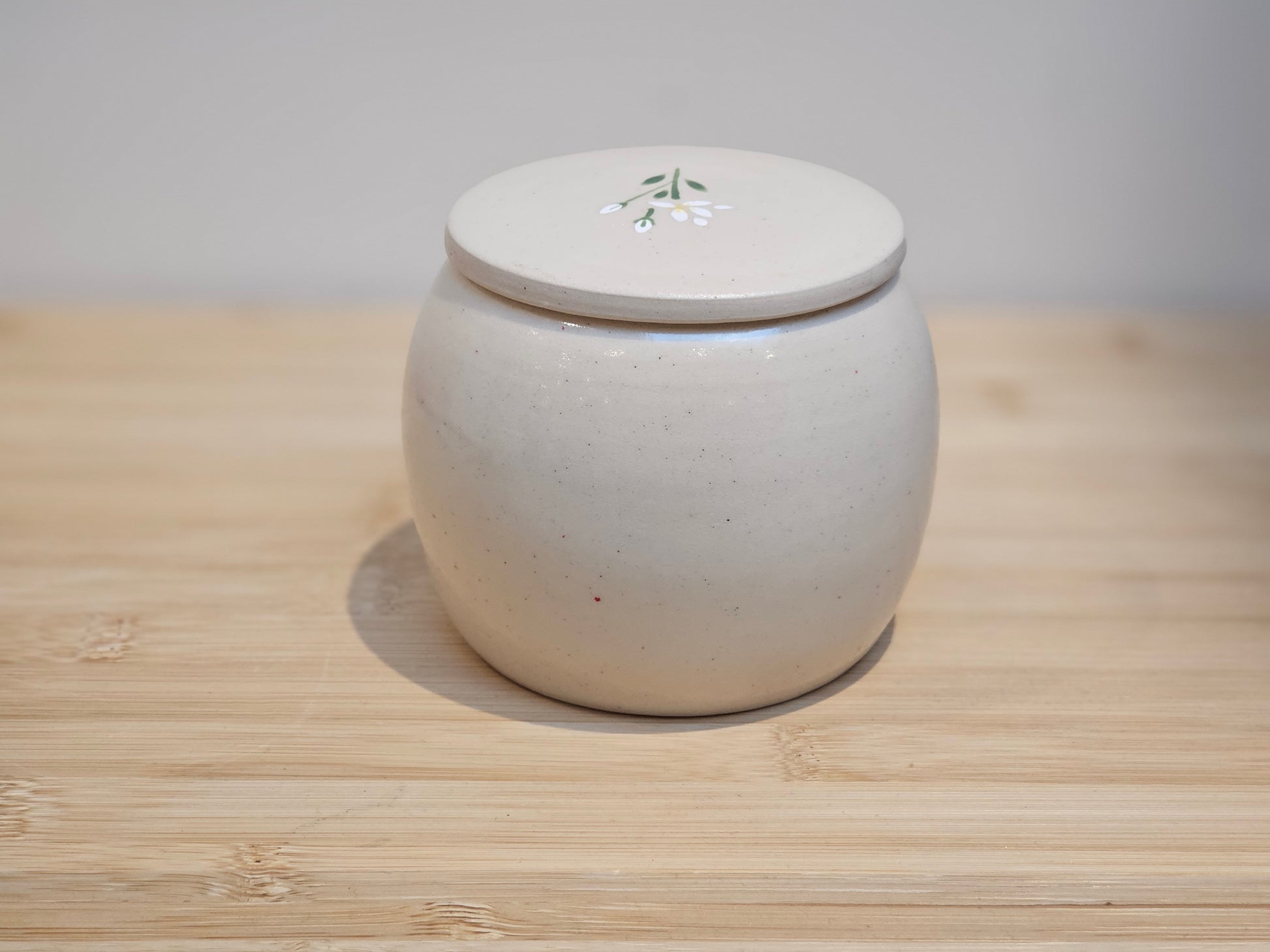 Hand-painted ceramic pet urn decorated with white lilies, personalised memorial keepsake