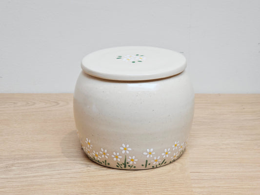 Ceramic jar with floral designs on a wooden surface