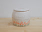 Handmade ceramic pet urn with orange flowers hand-painted around the entire bottom, perfect personalized memorial keepsake for pets.