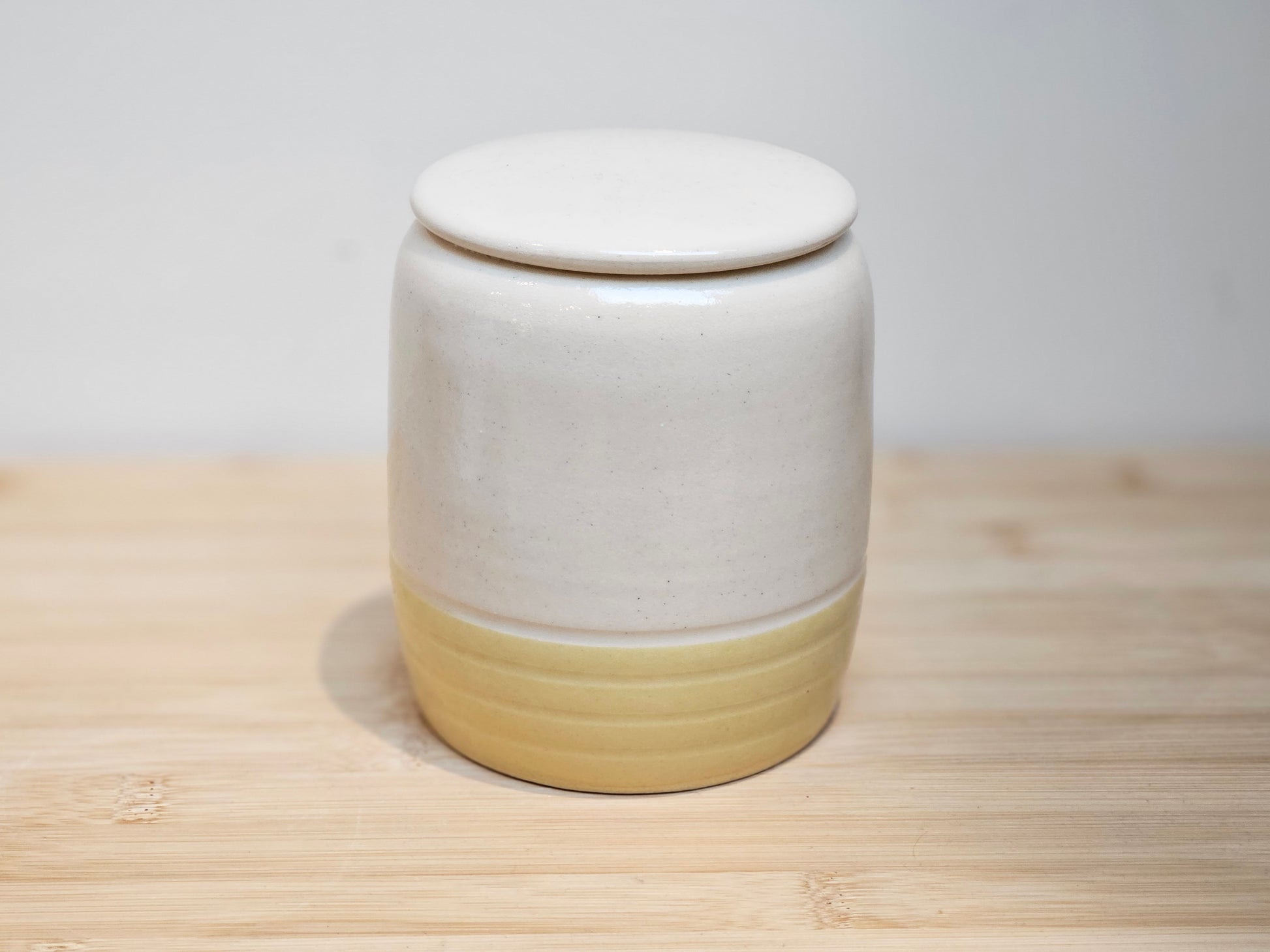 Side profile of custom ceramic pet urn highlighting the contrast between the soft yellow glaze and personalised upper design, handmade in the UK studio.