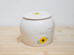White ceramic jar with sunflower design on a wooden surface