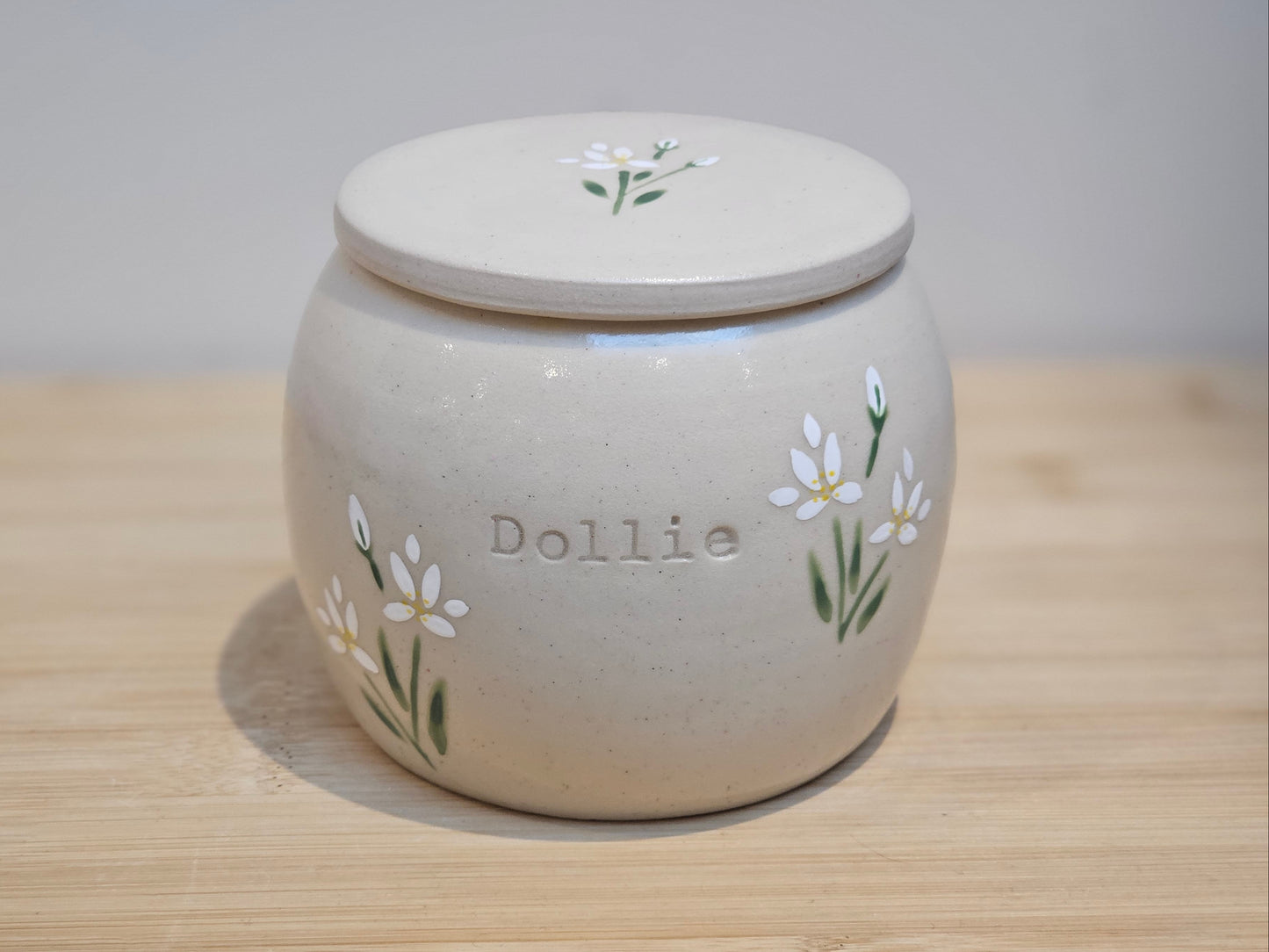 Handmade ceramic pet urn with hand-painted white lilies and personalised name detail