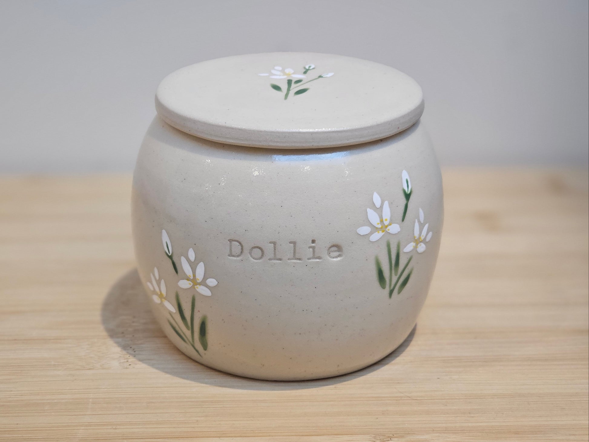 Handmade ceramic pet urn with hand-painted white lilies and personalised name detail