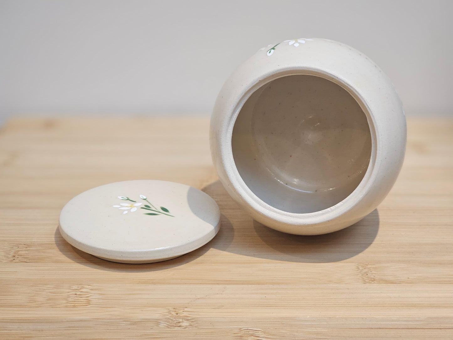 Personalised pet ashes urn featuring elegant white lily floral design, handcrafted pottery