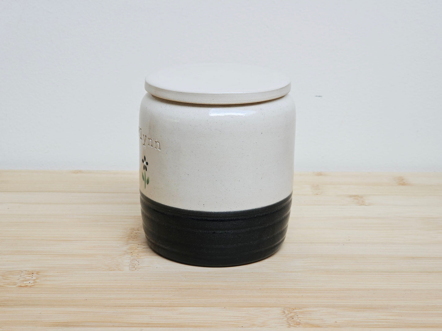 White and black ceramic container with personalised name engraved. 