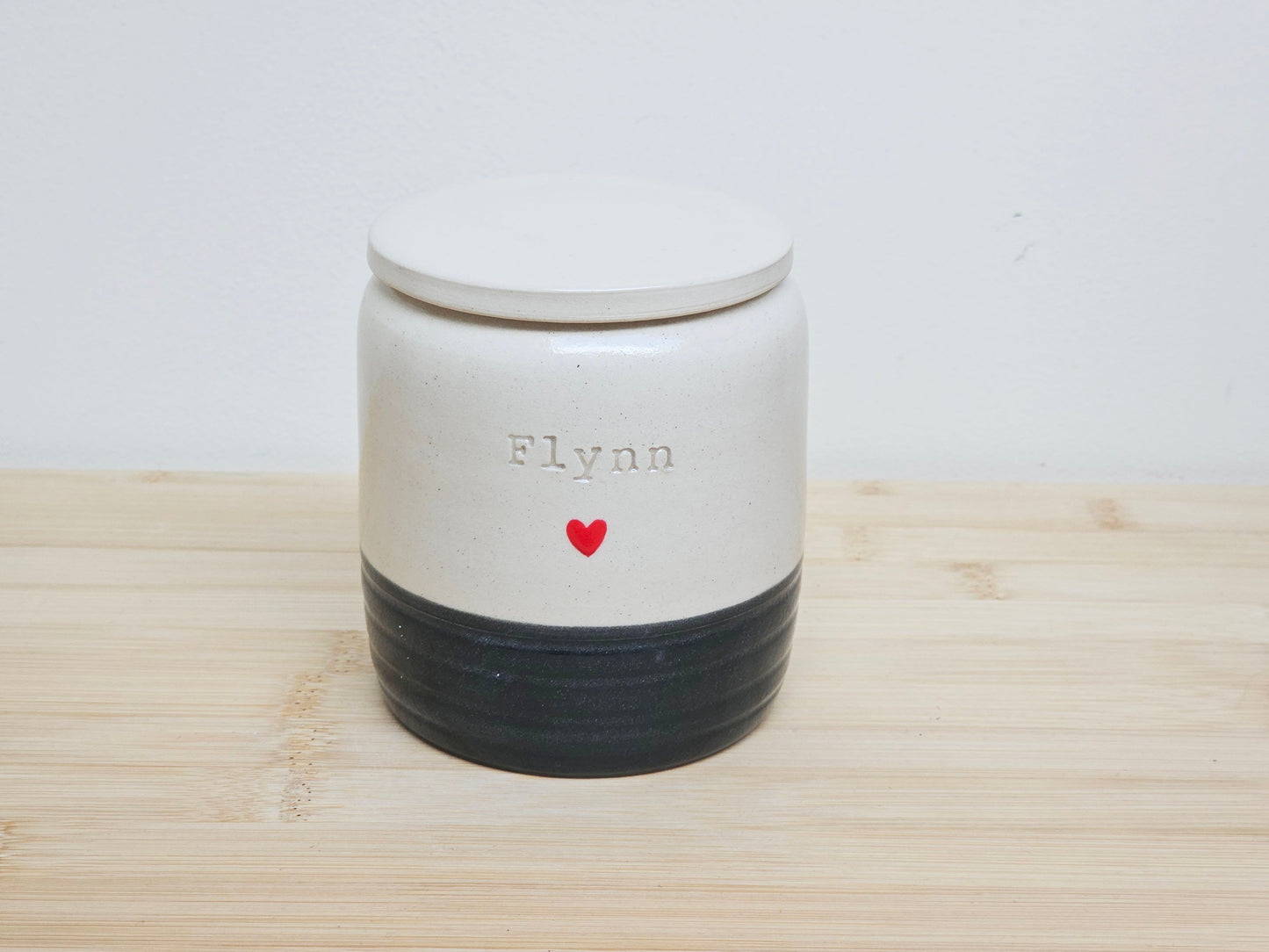 Custom pet urn with black base and 'Flynn' and handpainted heart design. This is a hand thrown personalised urn.