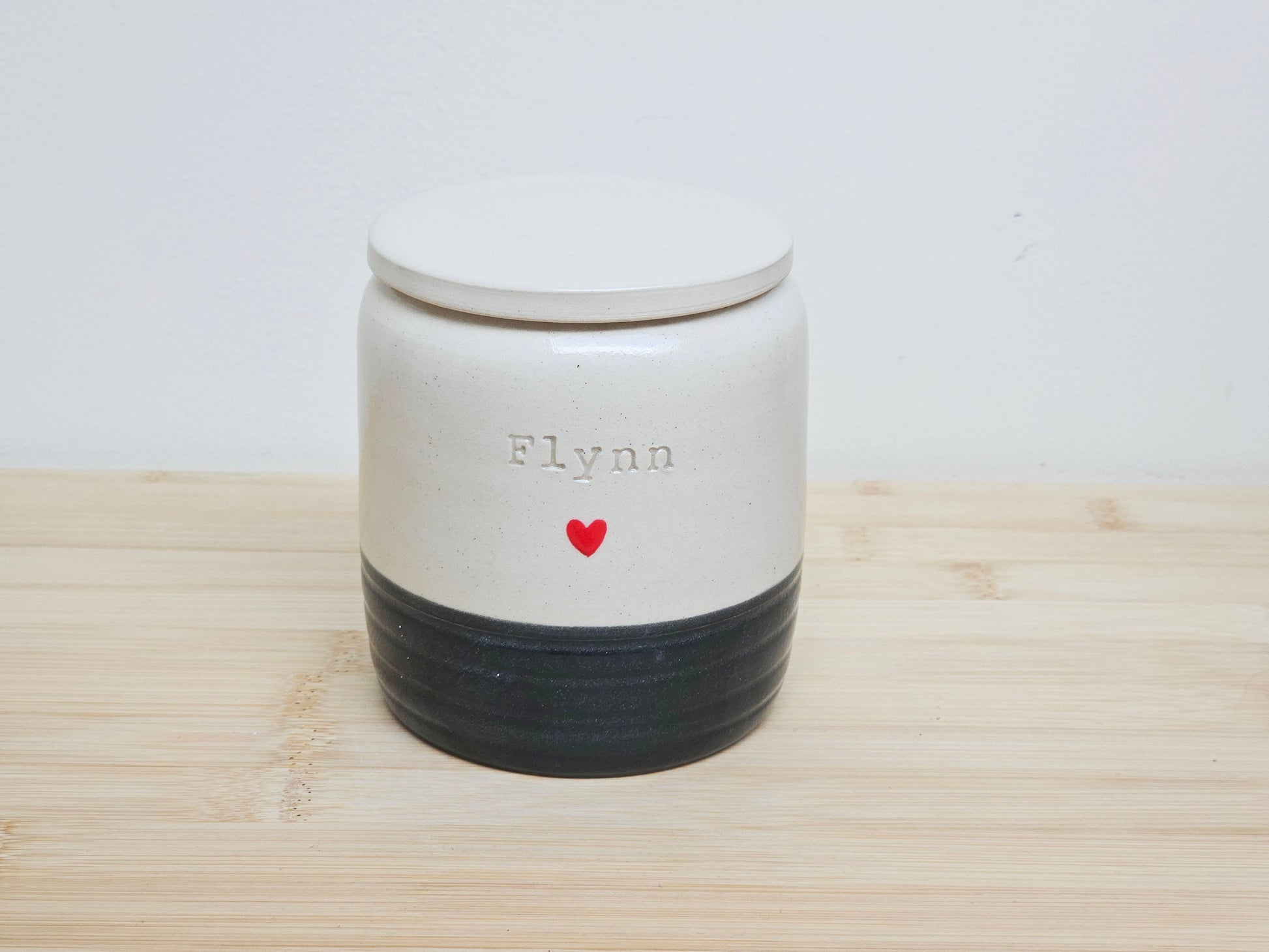 Custom pet urn with black base and 'Flynn' and handpainted heart design. This is a hand thrown personalised urn.