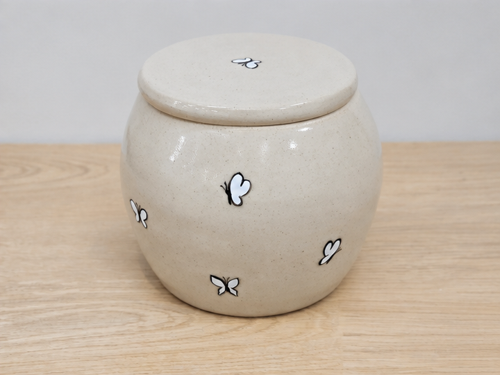 Memorial urn with butterfly designs on a wooden surface