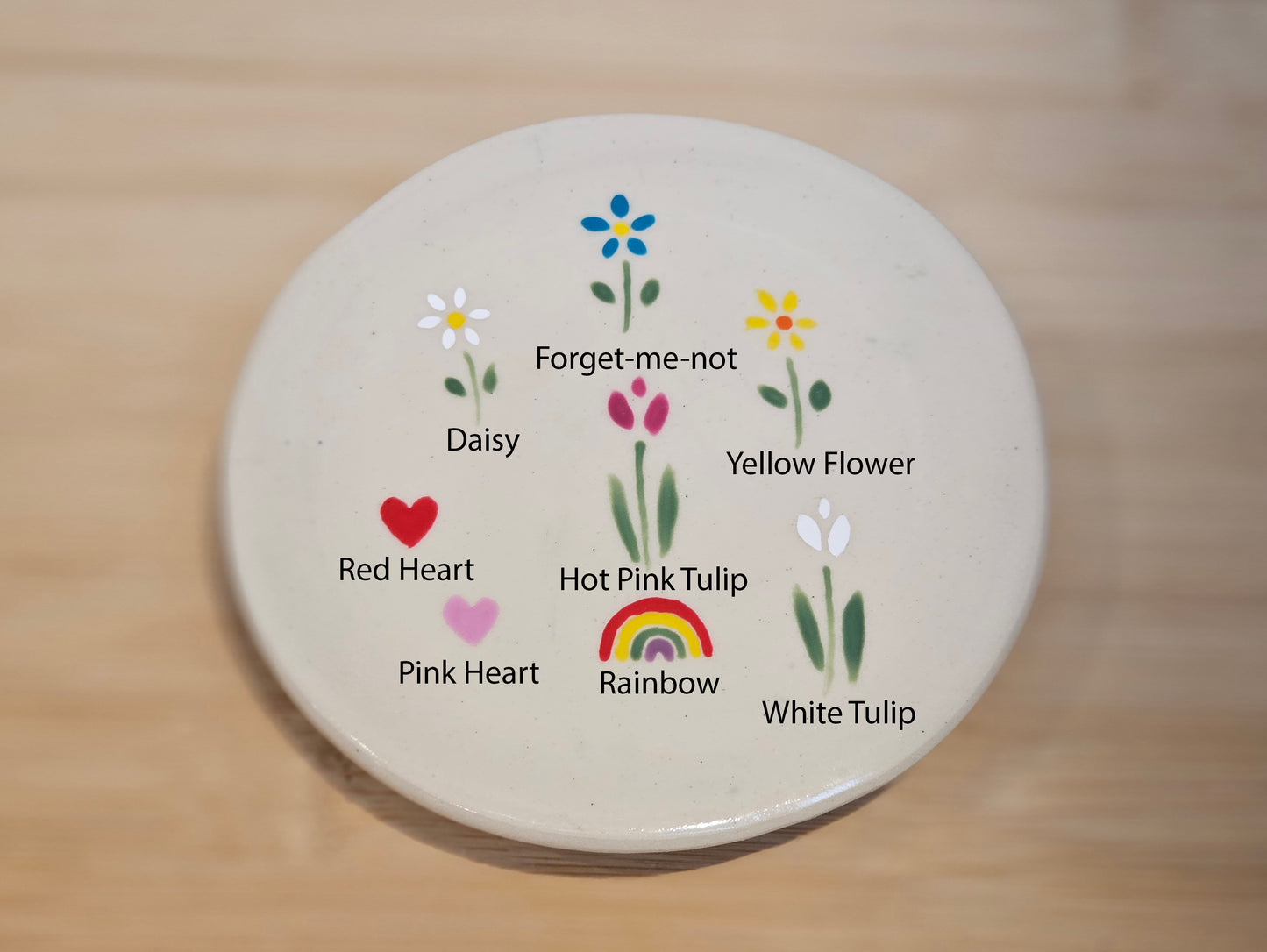 Round ceramic coaster with floral and heart designs on a wooden surface