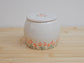 Handmade ceramic pet urn with orange flowers hand-painted around the entire bottom, perfect personalized memorial keepsake for pets.