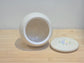 White ceramic urn with a lid on a wooden surface