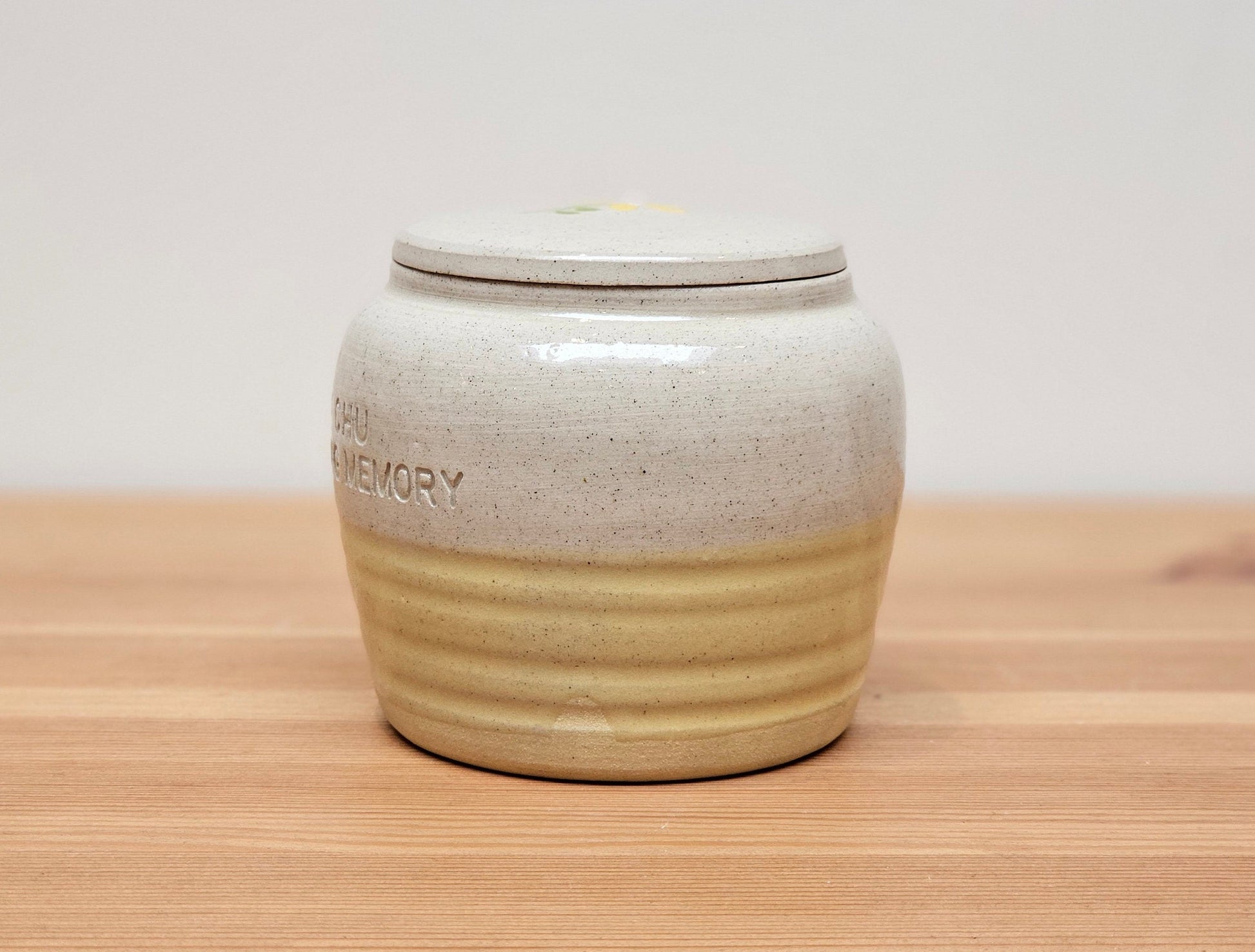 Handmade ceramic pet urn with a delicate hand-painted yellow flower design, featuring an option for name engraving to create a truly personalised memorial. This bespoke pottery urn is perfect for cat or dog ashes, offering a beautiful and secure resting place. With a smooth glazed finish and a snug-fitting lid, this custom pet cremation urn is a heartfelt tribute to your beloved companion.