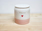 Ceramic jar in cream and pink, with 'Daisy'  stamped on the side and a heart on a wooden surface