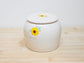 White ceramic cremation for dog and cat ashes with sunflower design and engraved name.