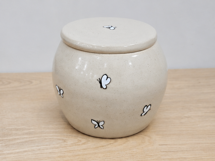 Keepsake urn with butterfly designs on a wooden surface
