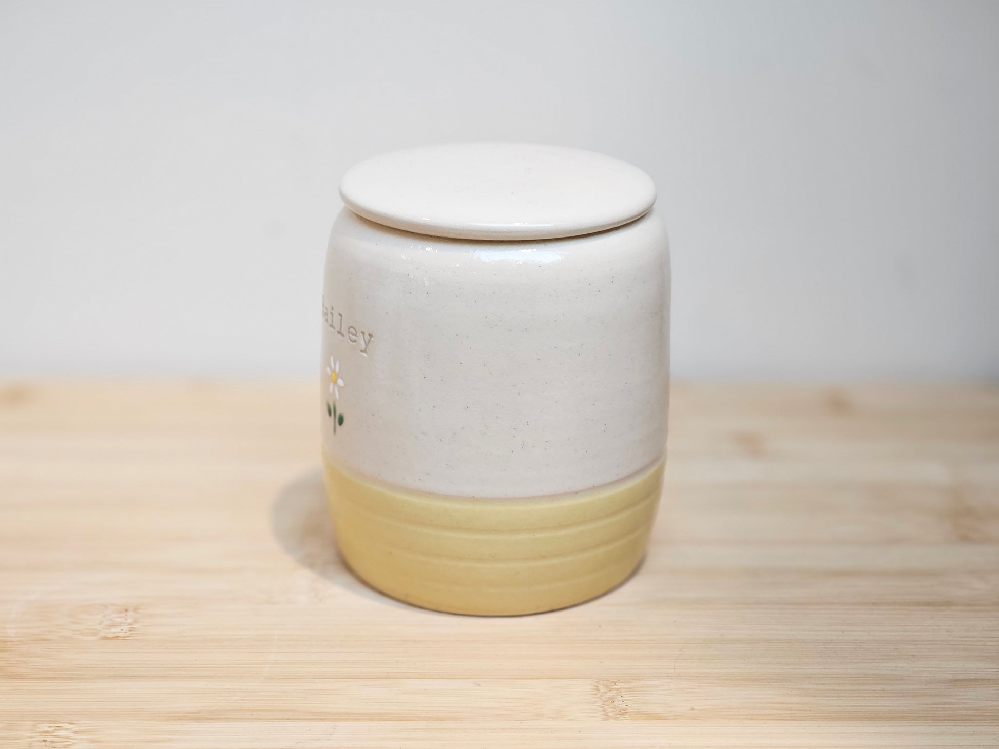 White and yellow ceramic jar with a lid on a wooden surface