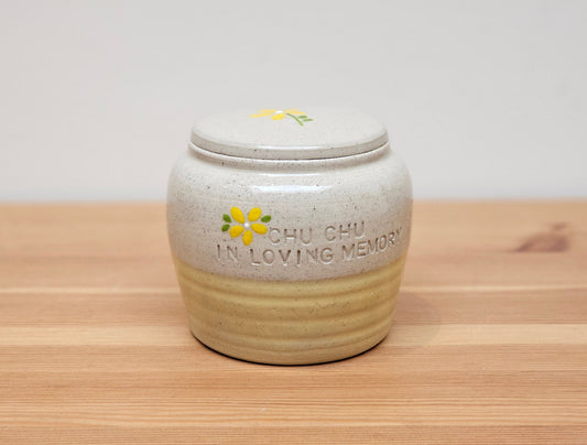 Handmade ceramic pet urn with a delicate hand-painted yellow flower design. This beautifully crafted pottery urn provides a dignified and elegant memorial for your beloved pet. Each urn is unique, featuring a smooth glazed finish and a secure lid to safely store ashes. Ideal for cat or dog ashes, this decorative pet cremation urn offers a timeless tribute to cherish their memory. Perfect for pet lovers seeking a personalised, handcrafted pet memorial.